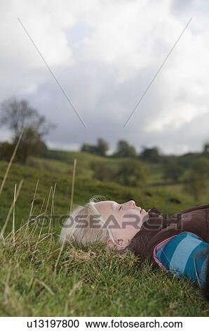 Girl lying on grass looking at sky View Large Photo Image Stock Image - Girl lying on grass looking at sky. Fotosearch