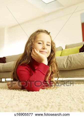 Stock Photo - "Girl lying on rug, looking to camera". Fotosearch