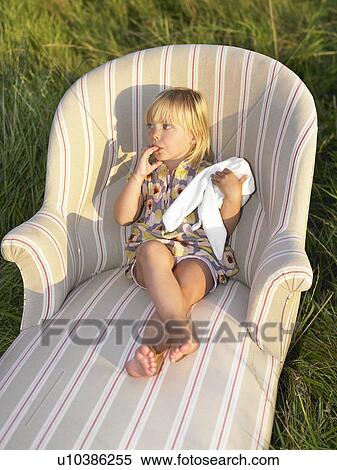 Stock Photography - Girl on sofa in a field. Fotosearch