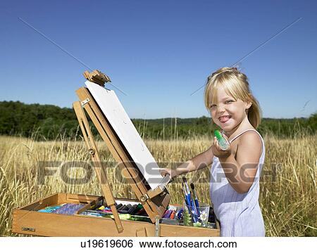 Stock Photograph - "Girl painting in a field, smiling". Fotosearch