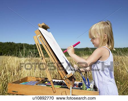 Girl painting in a field View Large Photo Image Stock Image - Girl painting in a field. Fotosearch