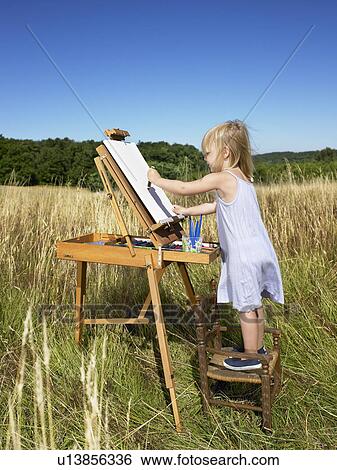 Stock Photograph - Girl painting in a field. Fotosearch