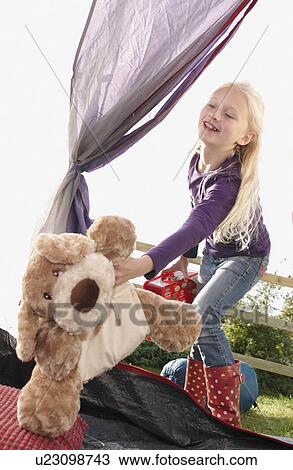 Stock Image - Girl putting toys in tent. Fotosearch