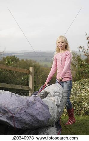 Stock Image - Girl putting up tent. Fotosearch