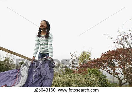 Stock Image - Girl putting up tent. Fotosearch