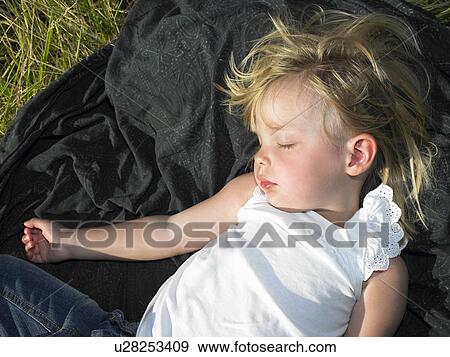 Stock Photo - "Girl sleeping in a field, under the sun". Fotosearch