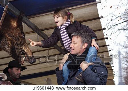 Stock Image - Girl touching boar's head at market. Fotosearch