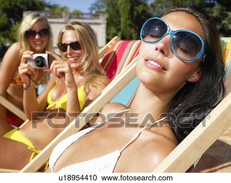 Stock Image - "Girlfriends around pool, taking pictures". Fotosearch