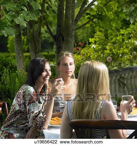 Stock Image - Girlfriends having lunch outdoors. Fotosearch