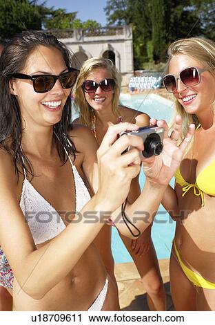 Girlfriends taking pictures around pool View Large Photo Image Stock Image - Girlfriends taking pictures around pool. Fotosearch