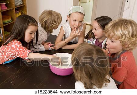Picture - Girls and boys tasting dish. Fotosearch