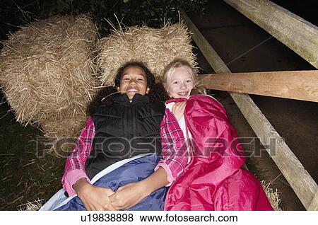 Stock Photo - Girls in sleeping bags on haybales. Fotosearch