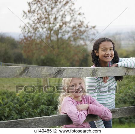 Stock Image - Girls on fence. Fotosearch