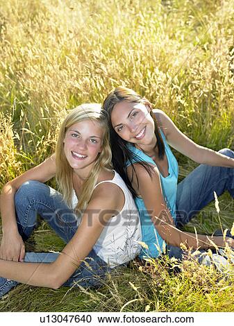 "Girls seated in a field, smiling" View Large Photo Image Stock Image - "Girls seated in a field, smiling". Fotosearch