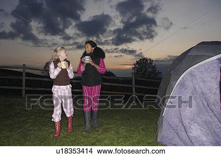 Picture - Girls walking to tent at dusk. Fotosearch