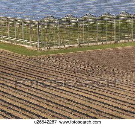 Stock Photo - Greenhouses in ploughed field. Fotosearch