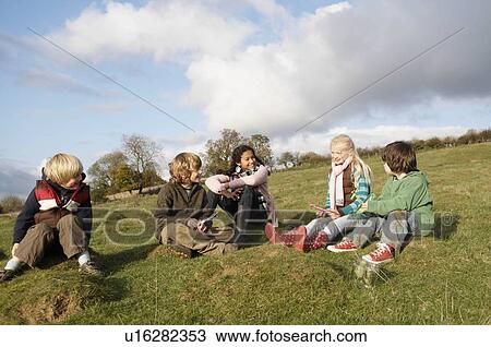 Stock Image - Group of children sitting on hill. Fotosearch