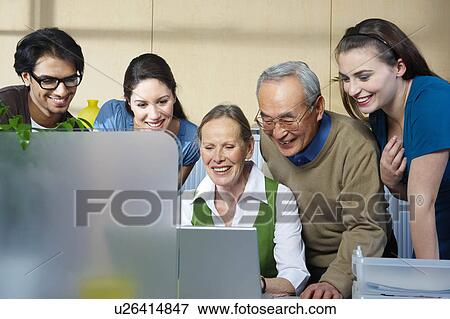 Stock Photo - Group of people looking at laptop. Fotosearch