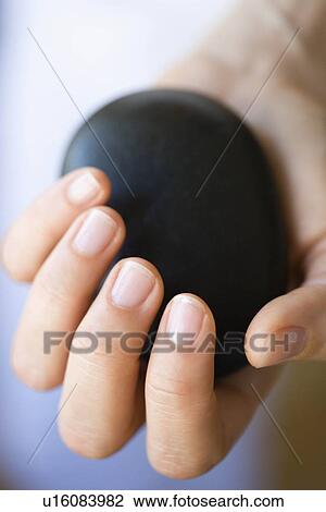 Stock Image - Hand holding hot stone. Fotosearch