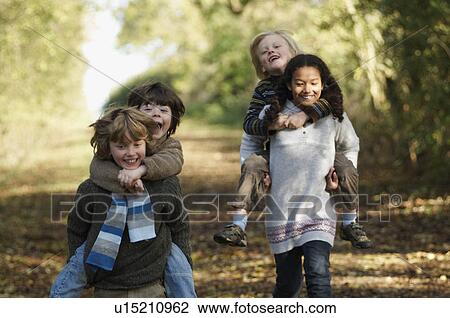 Stock Image - Kids in piggyback races on country lane. Fotosearch