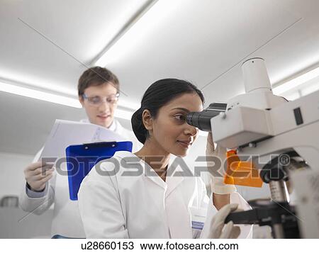 Stock Image - Laboratory technicians and microscope. Fotosearch