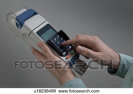Stock Photo - Male holding credit card machine. Fotosearch