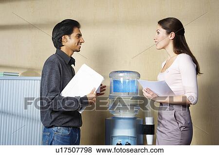 Man and woman chatting by water cooler View Large Photo Image Stock Photo - Man and woman chatting by water cooler. Fotosearch