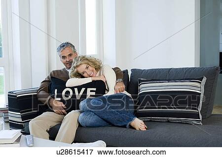 Stock Photo - Man and woman on sofa with cushion. Fotosearch