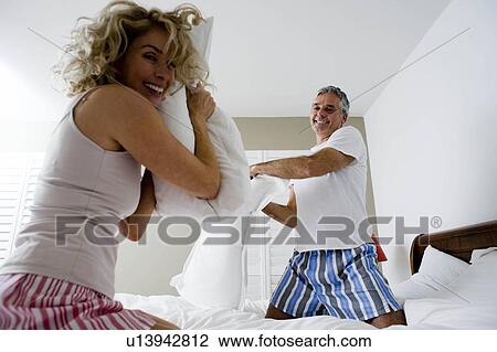 Stock Image - Man and woman pillow fighting. Fotosearch