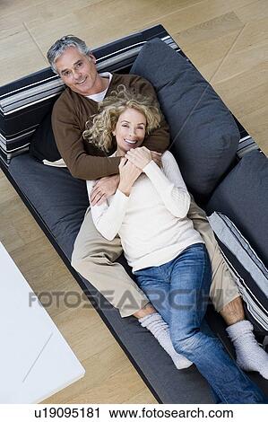 Stock Image - Man and woman relaxing on sofa. Fotosearch