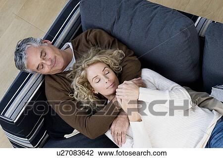 Stock Image - Man and woman relaxing on sofa. Fotosearch