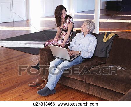 Stock Photograph - "Man and woman sitting on sofa, talking". Fotosearch