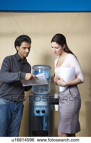 Stock Photograph - Man and woman standing by water cooler. Fotosearch