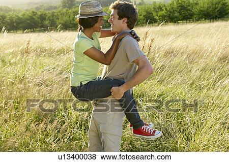 "Man carrying his woman, in a field" View Large Photo Image Stock Photo - "Man carrying his woman, in a field". Fotosearch
