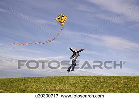 "Man jumping, flying a kite" View Large Photo Image Stock Photo - "Man jumping, flying a kite". Fotosearch