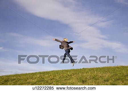 Man jumping into distance on grass View Large Photo Image Stock Photography - Man jumping into distance on grass. Fotosearch