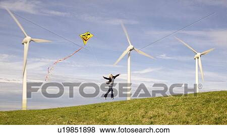 Man jumping with kite at Wind Turbines View Large Photo Image Stock Photo - Man jumping with kite at Wind Turbines. Fotosearch
