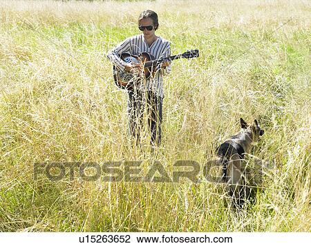 Man playing guitar in a field View Large Photo Image Stock Image - Man playing guitar in a field. Fotosearch