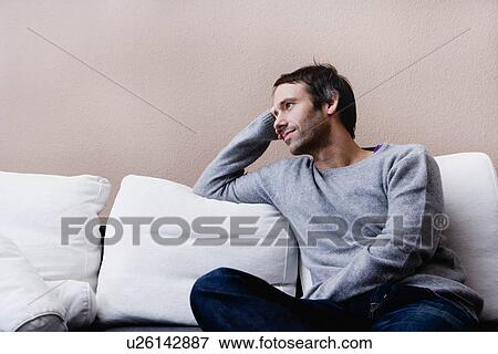 Stock Photo - Man sitting on couch. Fotosearch