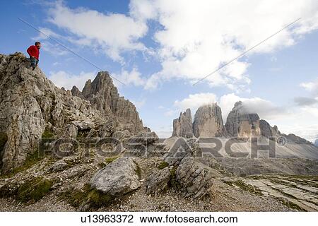 Man standing on rocks looking at peaks View Large Photo Image Stock Image - Man standing on rocks looking at peaks. Fotosearch