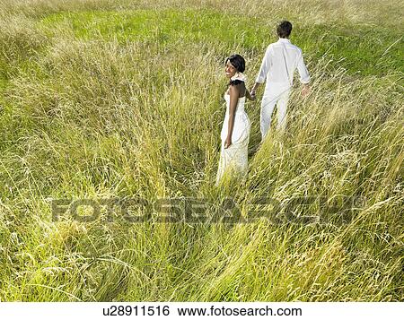 Stock Photograph - Married couple walking in a field. Fotosearch