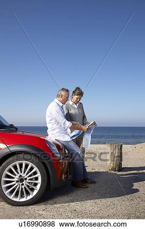 Mature couple looking at map by car View Large Photo Image Stock Photo - Mature couple looking at map by car. Fotosearch