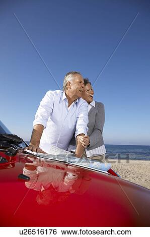Stock Photograph - Mature couple looking at map by car. Fotosearch