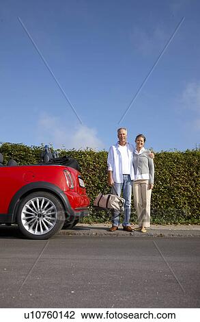 Stock Image - Mature couple standing next to car. Fotosearch