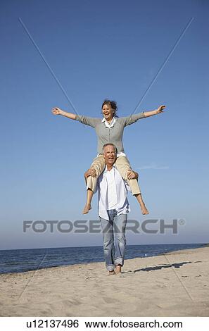 Stock Photograph - Mature couple walking along beach. Fotosearch