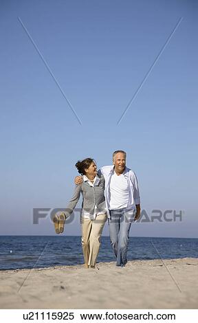 Mature couple walking along beach View Large Photo Image Stock Photography - Mature couple walking along beach. Fotosearch