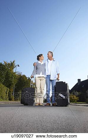Stock Photo - Mature couple with wheelie cases. Fotosearch