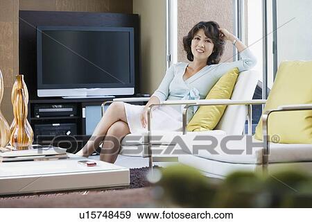 Mature woman relaxing in living room View Large Photo Image Stock Photo - Mature woman relaxing in living room. Fotosearch