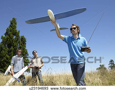 Stock Image - Men playing with remote-controlled plane. Fotosearch