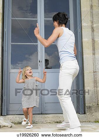 Stock Image - "Mother and daughter dancing, outdoors". Fotosearch
